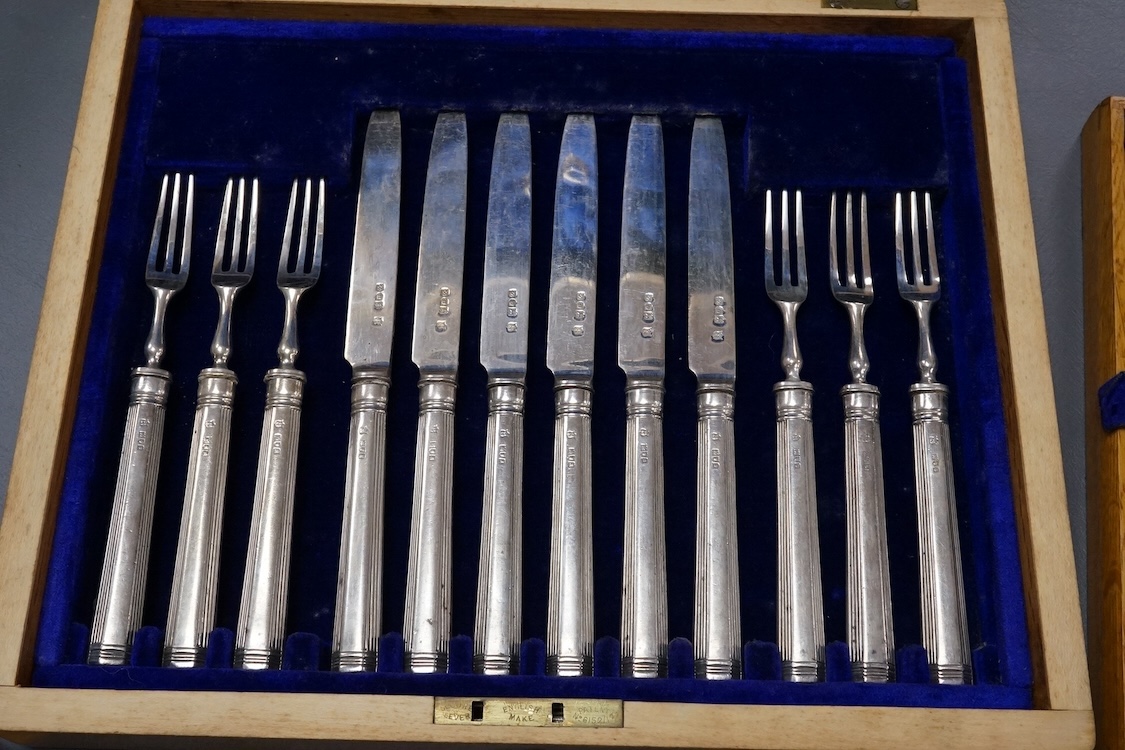 A set of twelve pairs of silver dessert eaters, by Thomas Bradbury & Sons, London, 1913, knife 19.8cm, handles loaded, housed in a fitted oak canteen.